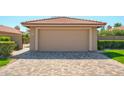 Beige two-car garage with a terra cotta roof and a paved driveway at 8877 E Riviera Dr, Scottsdale, AZ 85260
