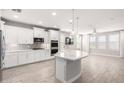 Bright kitchen with white cabinetry, stainless appliances, and a large island with pendant lighting at 13660 N 144Th Ln, Surprise, AZ 85379