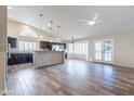 Open-concept space including living, dining, and kitchen with wood-look tile, large windows, and modern ceiling fans at 14443 W Morning Star Trl, Surprise, AZ 85374