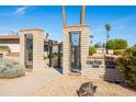 Close-up view of the Cactus Court entrance with brick walls, wrought iron gates, and manicured shrubs at 16827 N 103Rd Ave, Sun City, AZ 85351