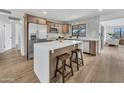 Bright kitchen featuring an island with seating, stainless steel refrigerator, and wood-look flooring at 3517 E Hartford Ave, Phoenix, AZ 85032