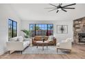 Spacious living room with a stone fireplace, modern furniture, and bright natural light from large windows at 3517 E Hartford Ave, Phoenix, AZ 85032