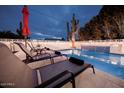 Evening view of the lit pool area, complete with a waterfall feature and lounge chairs at 8725 E Vista Dr, Scottsdale, AZ 85250