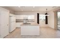 Bright kitchen featuring white cabinets, island with sink, and a window offering natural light at 9512 E Kilarea Ave, Mesa, AZ 85209