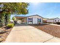 Exterior view of a white home with covered parking, featuring a well-kept yard and long driveway at 1061 S Palo Verde St, Mesa, AZ 85208