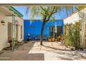 Tranquil courtyard with a blue accent wall, mature tree, potted plants, and comfortable seating area at 1401 E Griswold Rd, Phoenix, AZ 85020