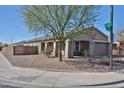 Corner lot home featuring desert landscaping, a covered porch, and mature trees for added curb appeal at 20231 W Grant St, Buckeye, AZ 85326