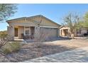 Attractive single-story home with desert landscaping, a covered porch, and a brick paver driveway at 20231 W Grant St, Buckeye, AZ 85326