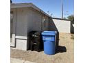 Shows the corner of the home with trash and recycling bins, minimal landscaping and a solid block wall at 3018 W Rancho Dr, Phoenix, AZ 85017