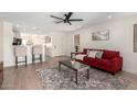 Open-concept living room with hardwood floors, ceiling fan, and a cozy seating area at 43795 W Sagebrush Trl, Maricopa, AZ 85138