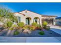 Single-story home with arched entryway, desert landscaping and flowering bushes with a stucco exterior and attached garage at 5245 N 205Th Ln, Buckeye, AZ 85396