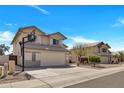 Charming two-story home with a well-maintained front yard, two car garage and blue sky at 5611 W Blackhawk Dr, Glendale, AZ 85308