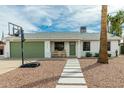 Charming single-story home with desert landscaping, walkway, a basketball hoop, and a green garage door at 1347 S Almond Cir, Mesa, AZ 85204