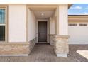Welcoming front entryway featuring a covered porch with brick accents and a modern front door at 16749 W Whispering Wind Dr, Surprise, AZ 85387