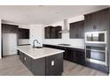 Modern kitchen features an island, stainless steel appliances, dark wood cabinets, and white countertops at 16749 W Whispering Wind Dr, Surprise, AZ 85387