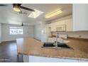 Bright kitchen featuring a skylight, sleek countertops, and views into the living area at 7737 W Medlock Dr, Glendale, AZ 85303