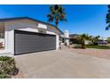 This shot focuses on the house's garage, driveway, and a small desert-style garden with rocks at 10934 E Becker Ln, Scottsdale, AZ 85259