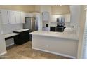 Modern kitchen with white upper cabinets and dark lower cabinets, stainless steel appliances and quartz countertops at 11564 W Mule Deer Ct, Surprise, AZ 85378