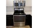 Close up of stainless steel stove and microwave with white subway tile backsplash and white countertops at 11564 W Mule Deer Ct, Surprise, AZ 85378