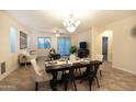 Open dining room with modern table set, chandelier, and seamless flow into the living space at 12030 W Louise Ct, Sun City, AZ 85373