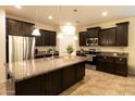 Modern kitchen featuring dark cabinets, granite countertops, stainless steel appliances, and large island at 12030 W Louise Ct, Sun City, AZ 85373