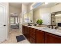 Well-lit bathroom with double sinks, a large mirror, and a view of the bedroom at 16390 W Sheila Ln, Goodyear, AZ 85395