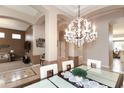 Beautiful chandelier above a glass dining table that sits 6 with lots of natural light and tile/wood floors at 301 E Ashurst Dr, Phoenix, AZ 85048