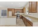 Well-lit kitchen featuring tile floors, an island, granite counters, and sleek stainless steel appliances at 3911 S 100Th Gln, Tolleson, AZ 85353