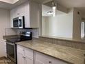 Bright kitchen with white cabinets, stainless steel appliances and granite countertops open to living area at 850 S River Dr # 2018, Tempe, AZ 85281