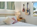 Stylish bedroom with a decorative bedside table, natural lighting, and two guitars hanging on the wall at 901 E Rose Ln, Phoenix, AZ 85014