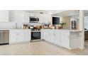 Contemporary kitchen featuring white cabinets, stainless steel appliances, and light wood-look flooring at 901 E Rose Ln, Phoenix, AZ 85014