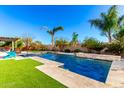 A private backyard featuring a pool, palm trees, and travertine decking offers relaxation and entertainment at 12055 W Nadine Way, Peoria, AZ 85383
