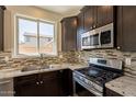 Well-lit kitchen featuring granite countertops, tile backsplash, stainless steel appliances, and dark cabinetry at 18123 W Lundberg St, Surprise, AZ 85388