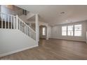 Bright, open living room with wood-look flooring, a staircase, and large windows allowing ample natural light at 18123 W Lundberg St, Surprise, AZ 85388