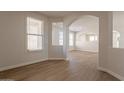 Open floor plan with archways, wood-look flooring, and abundant natural light from multiple windows at 18123 W Lundberg St, Surprise, AZ 85388