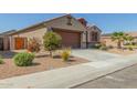 View of a single-story home, complimented by mature landscaping, a paved driveway, and tile roof at 2424 S 235Th Dr, Buckeye, AZ 85326