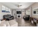 Spacious living room featuring a fireplace, a ceiling fan, and comfortable black leather seating at 2765 E Gillcrest Rd, Gilbert, AZ 85298
