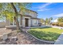 Well-maintained home featuring a lush green lawn, mature tree, and neutral-colored facade with stone accents at 3419 E Rosa Ln, Gilbert, AZ 85297