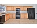 Functional kitchen featuring wood cabinetry, black appliances, and tiled flooring for easy maintenance at 44917 W Zion Rd, Maricopa, AZ 85139