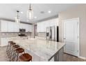 Modern kitchen with a large granite island, stainless steel appliances, and white cabinetry at 8515 W Peppertree Ln, Glendale, AZ 85305