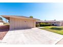 Attached garage with concrete driveway and lush, well-maintained landscaping at 10420 W Tropicana Cir, Sun City, AZ 85351