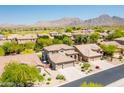 Stunning aerial view of a desert community with mountain backdrop, homes featuring tile roofs and desert landscaping at 10558 E Meadowhill Dr, Scottsdale, AZ 85255