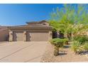 A beautiful home with a three-car garage and well-maintained desert landscaping with desert trees and native plants at 10558 E Meadowhill Dr, Scottsdale, AZ 85255