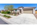 Inviting single-story home with a well-manicured lawn and desert landscaping leading to a two-car garage at 22854 E Pummelos Rd, Queen Creek, AZ 85142