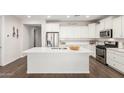 Modern kitchen with a large island, stainless steel appliances, custom cabinetry, and stylish tile backsplash at 22854 E Pummelos Rd, Queen Creek, AZ 85142