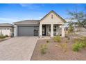 Inviting single-story home featuring a gray garage door, desert landscaping, and covered porch at 5644 N 206Th Gln, Buckeye, AZ 85396