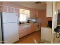 Cozy kitchen featuring pink and white cabinetry, a white refrigerator, and laminate wood flooring at 8600 E Broadway Rd # 22, Mesa, AZ 85208