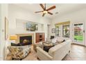 Cozy living room with fireplace, ceiling fan, comfortable seating, and view to the backyard at 17727 N 95Th Pl, Scottsdale, AZ 85255