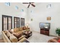 Bright living room with tall ceilings, many windows, plush sofa, and entertainment center at 17727 N 95Th Pl, Scottsdale, AZ 85255