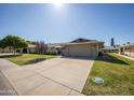 Inviting home featuring a well-kept lawn, mature landscaping, and attached two-car garage at 18835 N Mayan Dr, Sun City, AZ 85373